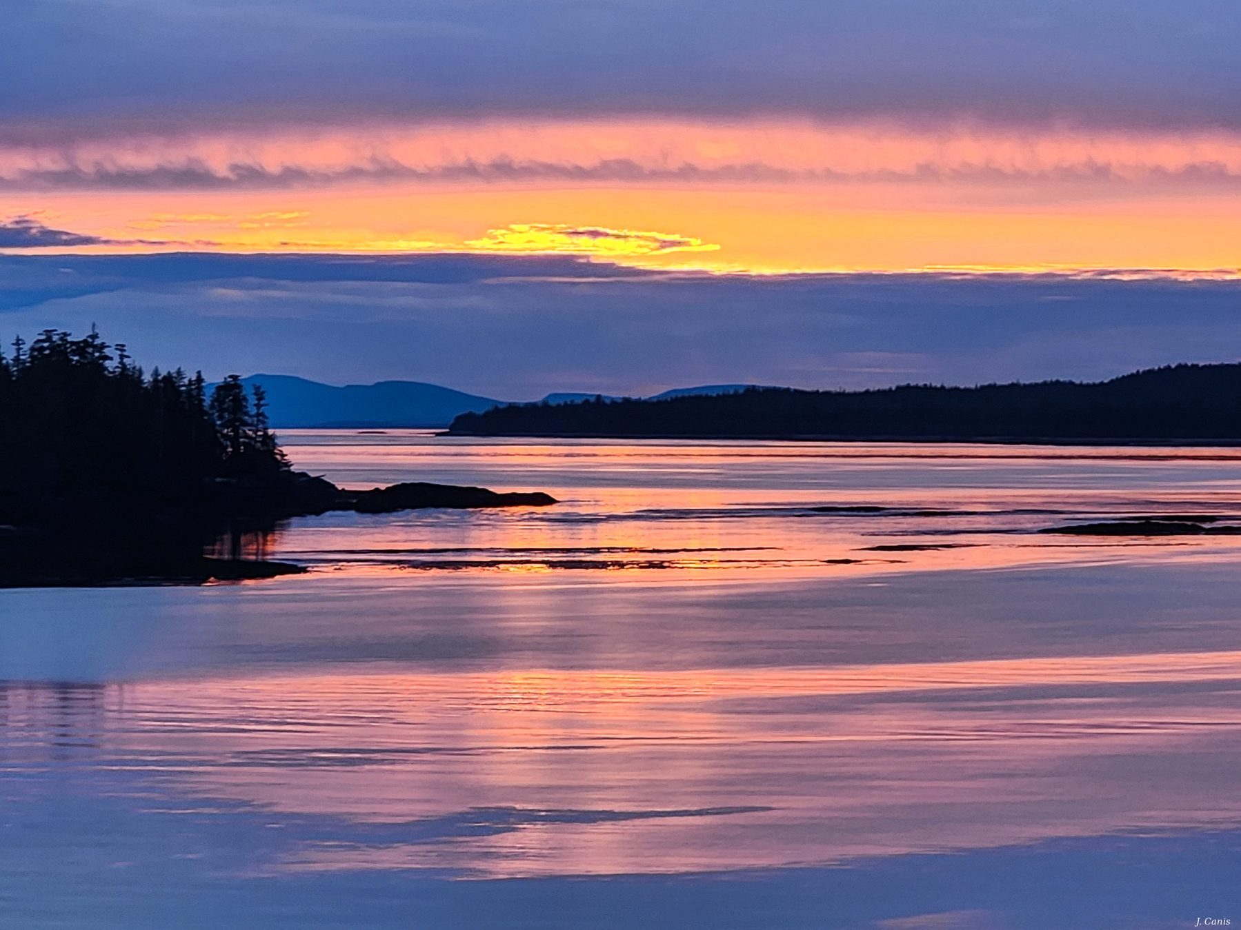 Alaska Reflection — firestorm sunset reflecting on calm Inside Passage waters, color photography by Jon Canis