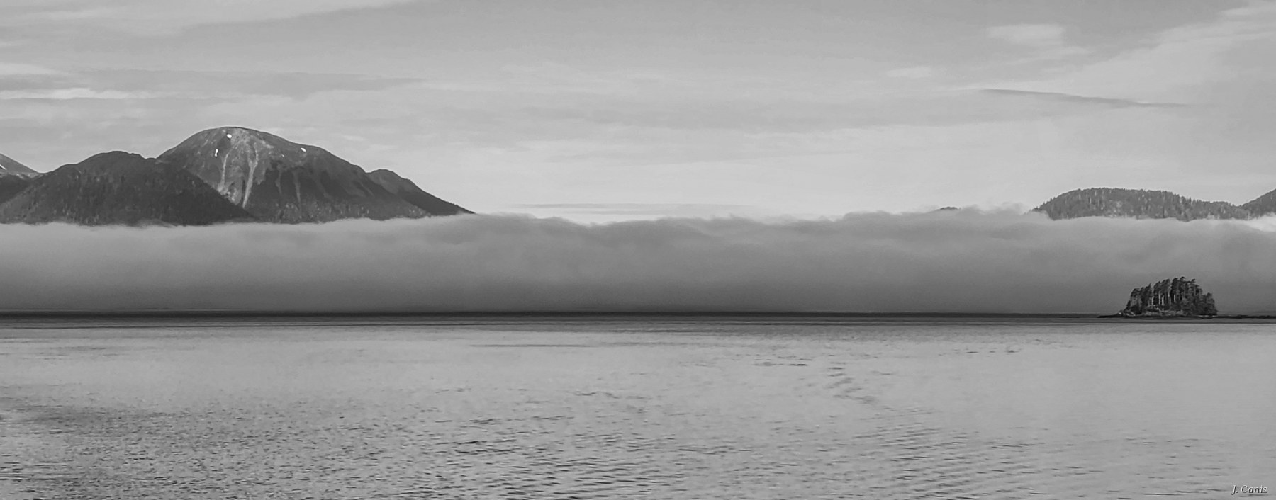 Alaska Fog Bank — fog layer rolling across Inside Passage between mountain peaks, black and white Alaska photography by Jon Canis