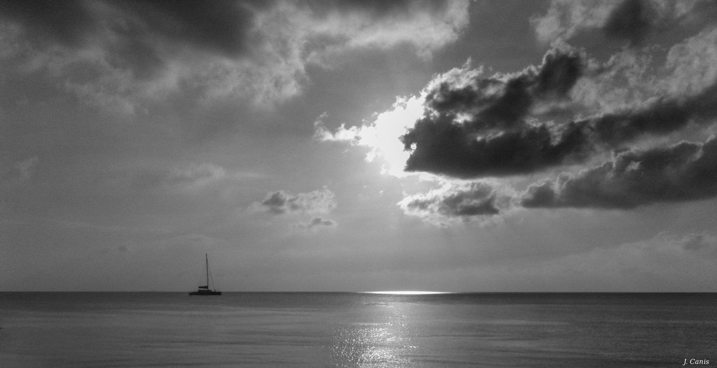 Sailboat — lone sailboat on calm Caribbean waters, black and white photography by Jon Canis