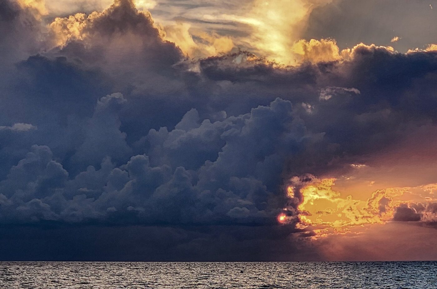 Cayman Light — sun breaking through storm clouds over Caribbean Sea, photography by Jon Canis