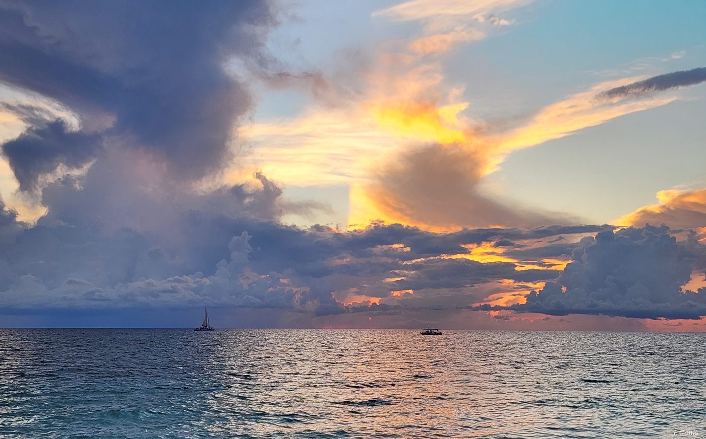 Cayman Sun — dramatic sunset with storm clouds and golden light over Caribbean Sea, photography by Jon Canis