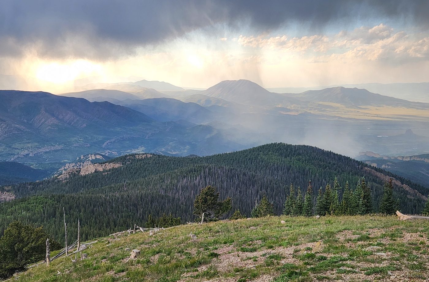 Rain Curtains — rain shafts falling across a deep Colorado valley from a high alpine meadow, photography by Jon Canis